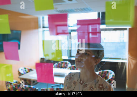 Female executive reading stick notes in office Stock Photo