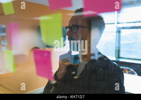 Male executive reading stick notes in office Stock Photo