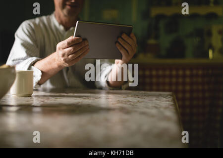 Senior man using digital tablet in kitchen at home Stock Photo