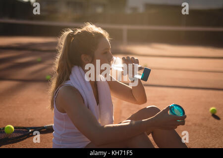 Tennis player drinking water after workout on a sunny day Stock Photo