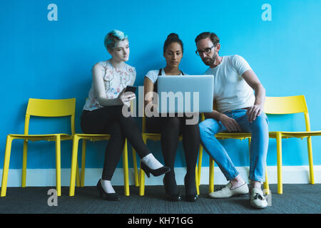 Executives discussing over laptop in office Stock Photo