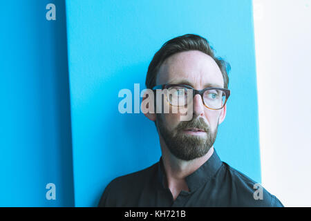 Thoughtful male executive standing against wall in office Stock Photo
