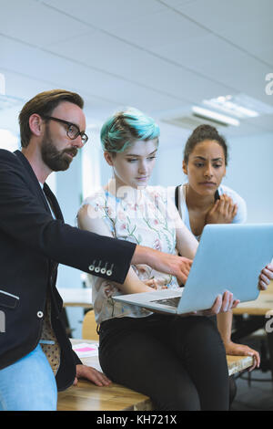Executives discussing over laptop in office Stock Photo