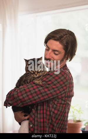 Man holding his cat in living room at home Stock Photo