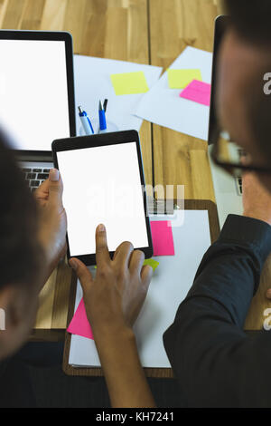 Executives using digital tablet at desk in office Stock Photo