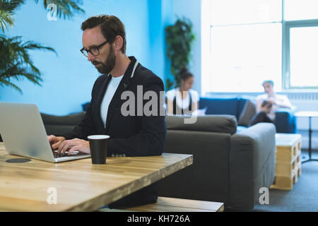 Male executive using laptop at desk in office Stock Photo