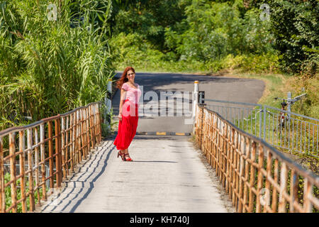 red-haired Irish girl walking on an old rusty iron bridge Stock Photo