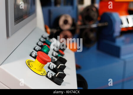 Control panel of the computer-aided manufacturing line. Selective focus on the emergency stop button. Stock Photo