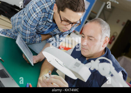 inspecting an object under magnifying lamp Stock Photo