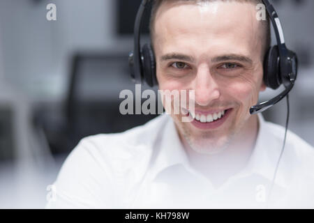 young smiling male call centre operator doing his job with a headset Stock Photo