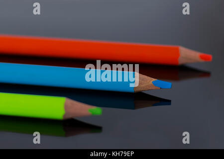 Multicolor pencils lie with reflection on black plexiglass Stock Photo