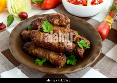 Juicy grilled rolls of minced meat wrapped in bacon. Stock Photo