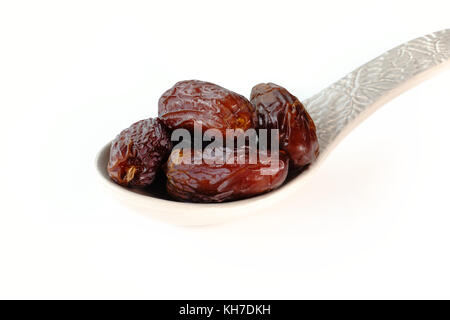 Closeup of several Medjool dates on a large grey ceramic spoon on white background with copy space. Stock Photo