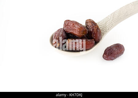 Medjool dates in a large grey ornamental ceramic spoon on white background with copy space. Stock Photo