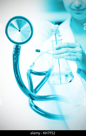 Blue stethoscope  against portrait of a female scientist shaking liquid in an erlenmeyer Stock Photo