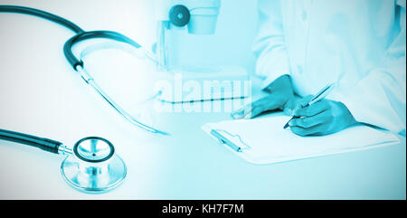 Metal black stethoscope against doctor writing on clipboard Stock Photo