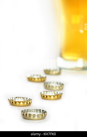 Few bottle caps on white background with beer glass Stock Photo