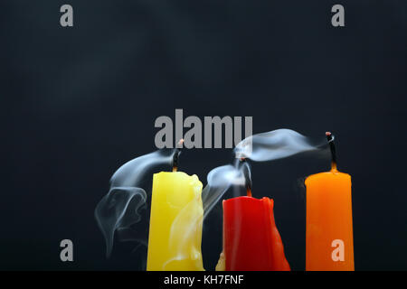 Three colored extinguished  candles with smoke on black background Stock Photo