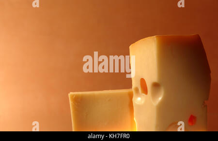 Two pieces of cheese against colorful gradient background with copy space Stock Photo