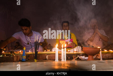 Dhaka, Bangladesh. 14th November 2017. Devotees attend prayer with burning incense and light oil lamps before break fasting during a religious festival called Rakher Upabash in near Dhaka on November 14, 2017. Bengali people of the Hindu faith in Bangladesh sit in prayer celebrating the 18th century Hindu Saint Baba Lokenath with a 'Rakher Upobas' prayer and fast day Every year thousands of Hindu devotees gather in front of Shri Shri Lokenath Brahmachari Ashram temple for the Rakher Upobash religious festival in Barodi, Near Dhaka, Bangladesh. Credit: Azim Khan Ronnie/Alamy Live News Stock Photo