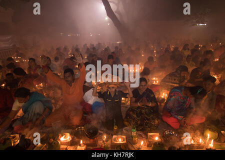 Dhaka, Bangladesh. 14th November 2017. Devotees attend prayer with burning incense and light oil lamps before break fasting during a religious festival called Rakher Upabash in near Dhaka on November 14, 2017. Bengali people of the Hindu faith in Bangladesh sit in prayer celebrating the 18th century Hindu Saint Baba Lokenath with a 'Rakher Upobas' prayer and fast day Every year thousands of Hindu devotees gather in front of Shri Shri Lokenath Brahmachari Ashram temple for the Rakher Upobash religious festival in Barodi, Near Dhaka, Bangladesh. Credit: Azim Khan Ronnie/Alamy Live News Stock Photo