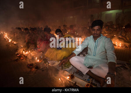 Dhaka, Bangladesh. 14th November 2017. Devotees attend prayer with burning incense and light oil lamps before break fasting during a religious festival called Rakher Upabash in near Dhaka on November 14, 2017. Bengali people of the Hindu faith in Bangladesh sit in prayer celebrating the 18th century Hindu Saint Baba Lokenath with a 'Rakher Upobas' prayer and fast day Every year thousands of Hindu devotees gather in front of Shri Shri Lokenath Brahmachari Ashram temple for the Rakher Upobash religious festival in Barodi, Near Dhaka, Bangladesh. Credit: Azim Khan Ronnie/Alamy Live News Stock Photo