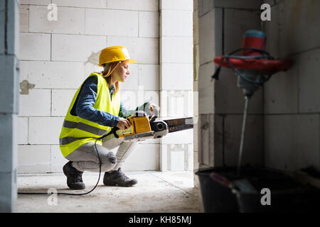 Young woman worker with saw on the construction site. Stock Photo