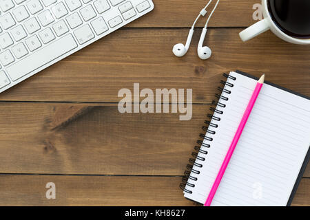 Computer keyboard notepad music earphones and coffee on wood desktop Stock Photo