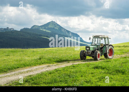 Old tractor on meadow. Beautiful mountain view in the Alps Stock Photo
