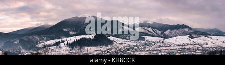 panorama of mountain ridge at sunrise. gorgeous winter landscape with high snowy peaks under the cloudy sky Stock Photo