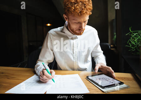 Shot of serious readhead young freelancer working at home Stock Photo