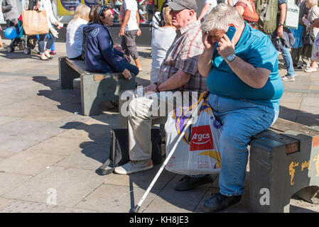 People sitting on benches in Northumberland Street, Newcastle city centre on a sunny day. Stock Photo
