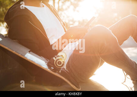 Cropped image of an african guy using mobile phone while having rest in urban zone Stock Photo