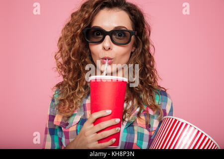 Portrait of serious lady in 3d glasses drinking cola and holding popcorn isolated Stock Photo