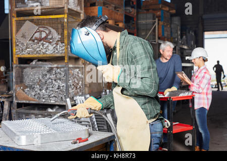 Metal factory workers and welders working together in workshop