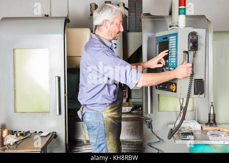 Worker programming CNC machine in metallurgy factory Stock Photo