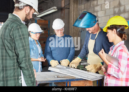 Craftsman and artisan teamwork in metallurgy workshop Stock Photo