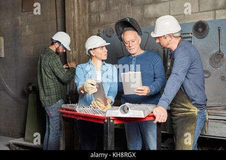 Team of workers planning in cooperation using tablet in metallurgy factory Stock Photo