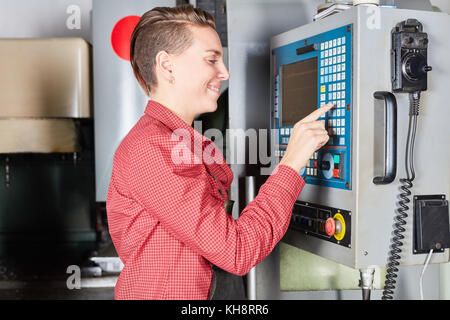 Young woman as worker using CNC machine in metallurgy factory Stock Photo