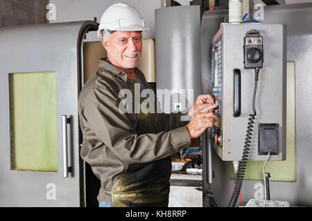 Senior man as blue collar worker and mechanist using CNC machine Stock Photo