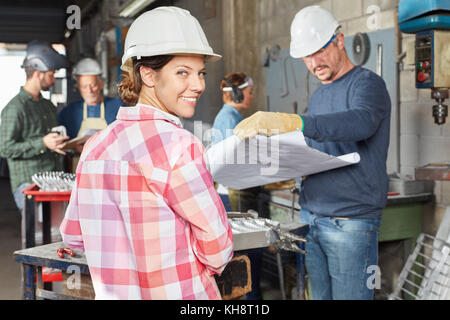 Young woman as blue collar worker apprentice in metallurgy workshop Stock Photo