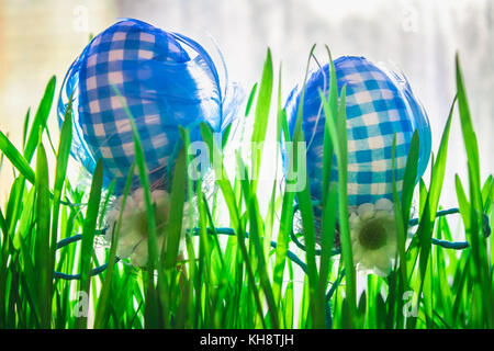 Decorative blue easter eggs in green grass on city background Stock Photo