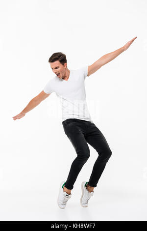 Full length portrait of a confident young man in white t-shirt posing while standing with hands outstretched isolated over white background Stock Photo
