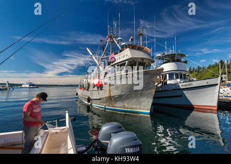 Young man cleaning boat after trip, fishing boats moored at marina in Quathiaski Cove on Quadra Island, Vancouver Island area, British Columbia, Canad Stock Photo
