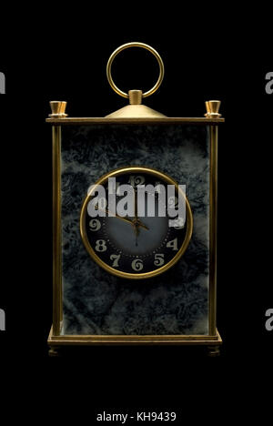 vintage massive desk clock in a block of gray stone (magnesite) with brass details on a black background Stock Photo