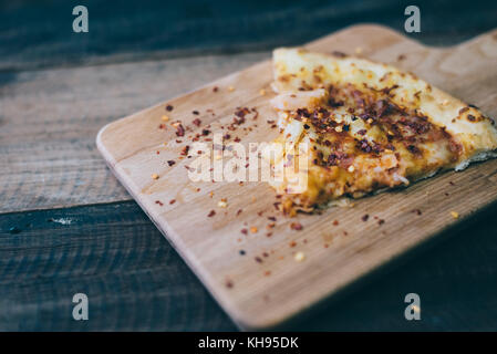 pizza slice with cheese,pineapple and chicken meat topping on a wooden board/table.famous italian food Stock Photo