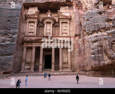 Pink sandstone Nabataean Treasury, Al Khazneh, carved from rock face in early morning with tourist taking a photo, Petra, Jordan, Middle East