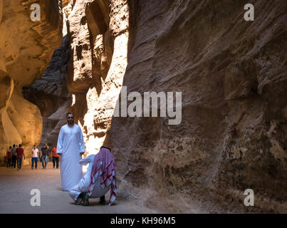 Arab man in traditional white robe and kufiya head dress taking a photo in the Siq gorge, Petra, Jordan, Middle East, Stock Photo