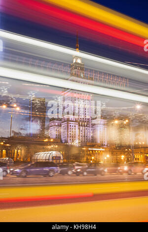 Abstract light trails in Warsaw city downtown at night in Poland, Palace of Culture and Science (Polish: Palac Kultury i Nauki) behind the lights. Stock Photo