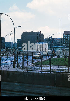 Photo taken in August 1965 showing view from the West German side of Berlin, across the Berlin Wall, to East Berlin in East Germany. Photo shows the wall covered in barbed wire and a military guard room. Stock Photo